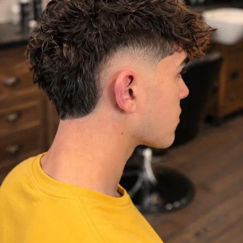Burst fade blowout haircut with voluminous textured hair and clean tapered sides