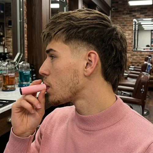 Burst fade mullet with straight hair, featuring a clean fade around the ears and a longer textured back.