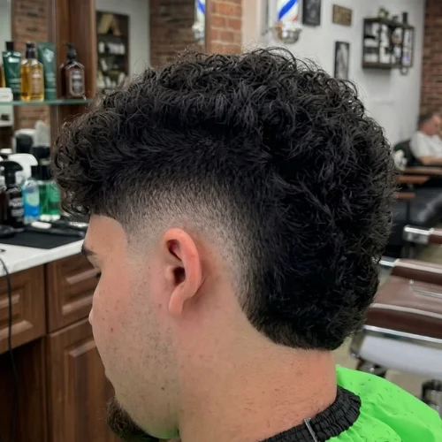 Man with a curly taper burst fade mullet haircut